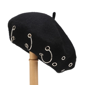 Detail of wool beret featuring silver metal rings and punk style eyelet decorations