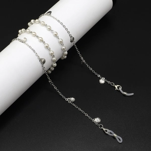 Chaîne à lunettes argentée avec perles et breloques coquillage sur support blanc