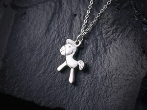 Vue macro d'un pendentif cheval argenté sur fond de pierre noire avec reflet métallique
