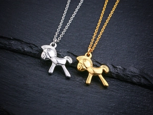 Détail macro de pendentifs cheval à bascule en or et argent sur pierre texturée