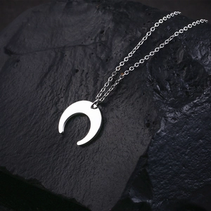 Minimalist silver crescent moon necklace on a black textured stone, elegant 18K gold plated jewelry