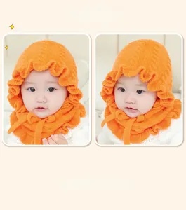 Detail view of orange baby knitted hood with wavy lace edges and secure matching chin ties
