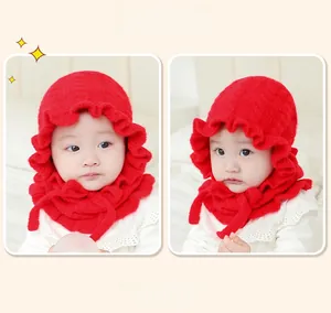 Close-up of red knit baby hat featuring ruffled brim details and soft chin ties