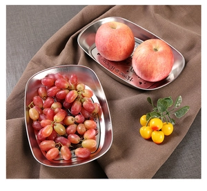 Macro detail of oval stainless steel serving trays with floral engravings and text