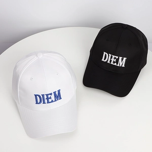 Black and white cotton baseball caps with DIEM embroidery on a round white table