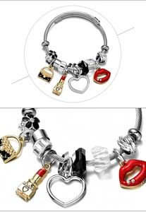 Detail view of woven steel bracelet with red lips and gold lipstick charms