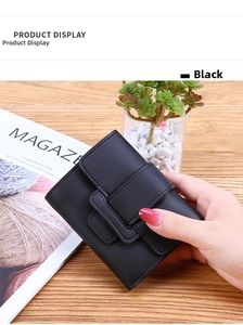 Detail of black tri-fold wallet showing soft lychee leather texture and secure strap closure