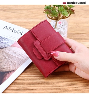 Detail of Bordeaux red tri-fold wallet with lychee pattern held against a wooden background