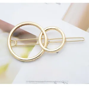 Detail shot of a minimalist double-loop gold metal hair clip with a polished finish