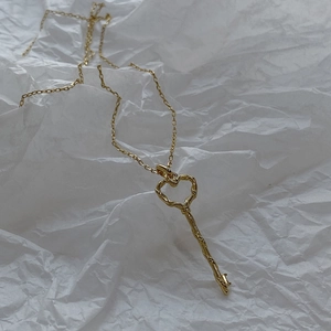 Minimalist 925 silver heart key pendant necklace in golden finish on white background
