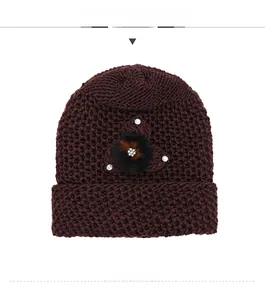 Detailed knit texture of burgundy winter hat with rhinestone-studded faux fur flower