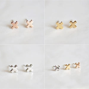 Detailed close-up of X-shaped titanium steel stud earrings in gold, rose gold and silver