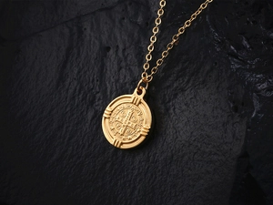 Détail du collier avec pendentif pièce en or 18 carats et motif en relief sur fond sombre