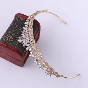 Close-up of golden bridal crown with leaf crystal detailing on a vintage jewelry box