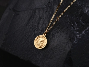 Gros plan d'un pendentif pièce en or 18K avec relief sur fond de roche