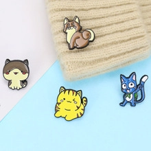Detail showing colorful enamel animal badges pinned on a beige knitted beanie hat