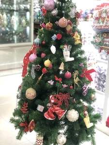 Close-up of a festive Christmas tree adorned with diverse colorful ornaments and bows
