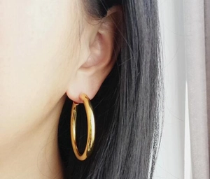Close-up of model wearing large golden hoop earrings in minimalist polished metal style