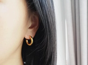 Close-up of chunky gold hoop earrings with high-polish finish on model ear