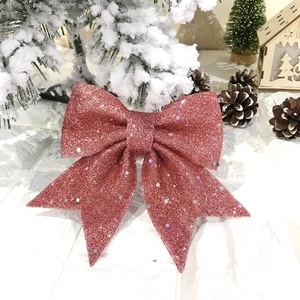Close-up of glittery pink Christmas bow decoration with sequins on a snowy winter background