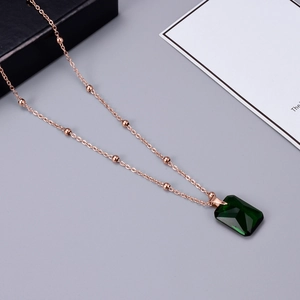 Macro view of rose gold necklace with large emerald-cut green zircon and beaded chain