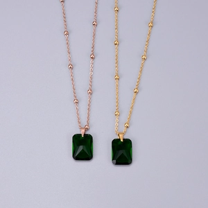 Detail of emerald green rectangular zircon pendants with gold and rose gold beaded chains