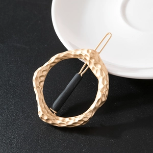 Macro shot of irregular matte gold alloy ring hair clip with hammered texture and pin