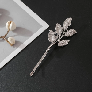 Detailed close-up of a silver metal leaf-shaped hair clip on a black background