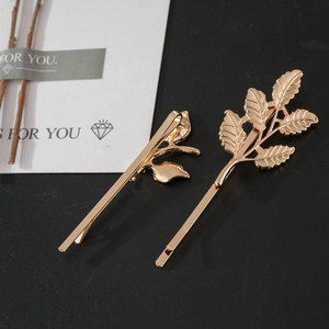 Detail of golden leaf hair clips featuring intricate vein textures on dark background