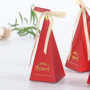 Detail of red marble texture wedding favor box with gold text and beige ribbon bow