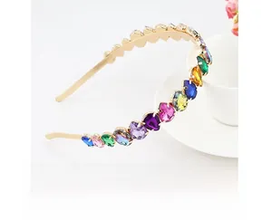 Detailed close-up of a gold metal headband with colorful teardrop gemstones and pearls