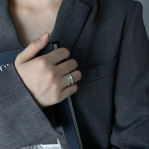 Detail of a textured 925 silver wide band ring worn by a model against a chic background