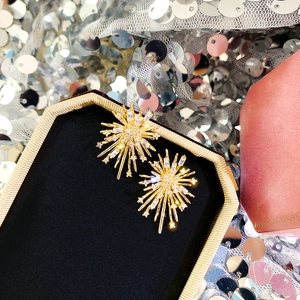 Detailed macro view of golden starburst fireworks earrings with sparkling zircons