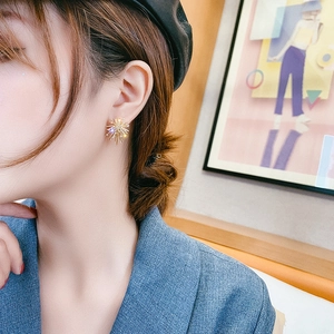 Detail view of model wearing golden firework stud earrings with sparkling cubic zirconia