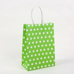 Detail view of green paper gift bag with white polka dots and sturdy paper handles