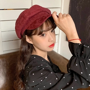 Detailed texture of burgundy suede fabric on a retro newsboy hat worn by a model