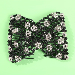 Detail of beaded magic hair comb with black and silver crystal bow on green background