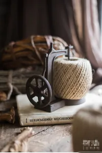 Vintage cast iron twine holder with natural jute rope on a rustic wooden desk