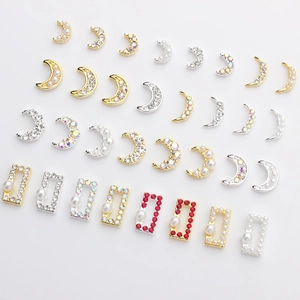Golden and silver moon-shaped nail charms with pearls and rhinestones on white background