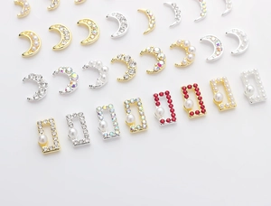 Macro shot of moon shaped nail charms with pearls and colorful rhinestones for DIY art
