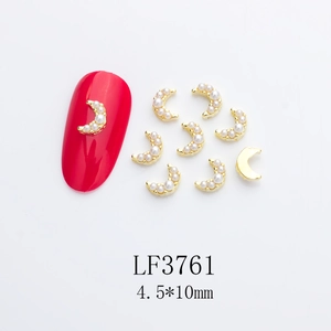 Detail of moon-shaped gold nail charms with white pearls for elegant DIY manicure