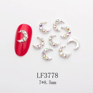 Macro view of moon-shaped silver nail charms with rainbow rhinestones on red nails