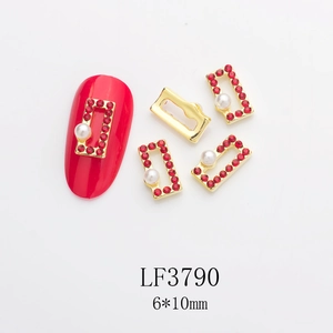 Detailed view of rectangle gold metal nail art charm with red rhinestones and white pearl
