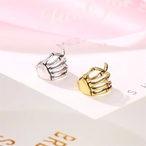 Punk style skull hand and spine ear cuff in silver and gold plating on white card