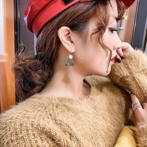 Ethnic style long tassel earrings in gold with colorful floral enamel details on model