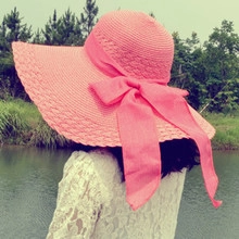 Close-up of coral pink wide-brim straw hat with elegant ribbon bow for sun protection