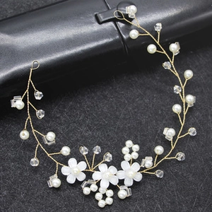 Close-up of handmade bridal hair clip with white flowers, gold wire and pearls
