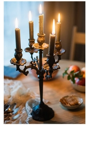 Detail van een vintage vijf-armige gietijzeren kandelaar met getextureerde kaarsen op de tafel