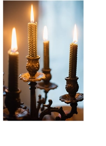 Detailopname van een vintage bronzen kandelaar met vier brandende honingraatkaarsen