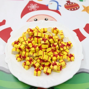 Macro shot of miniature yellow resin gift boxes with red bows on a white lace plate
